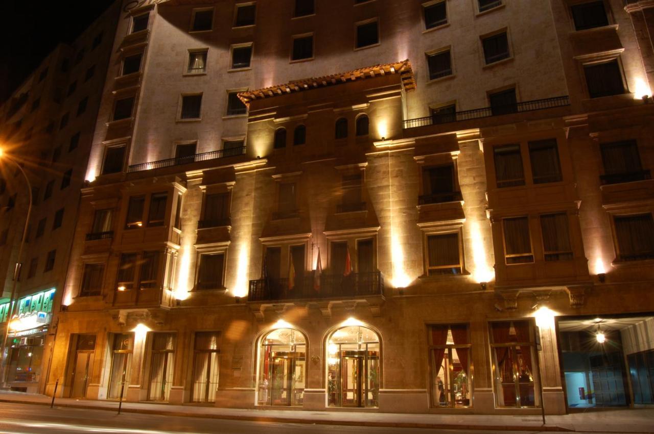 Hotel Alameda Palace Salamanca Exterior foto The photo shows the exterior of a building, likely a hotel, illuminated at night. The facade features a combination of decorative architectural elements, including a prominent entrance framed by large windows. Soft lighting highlights the building's 